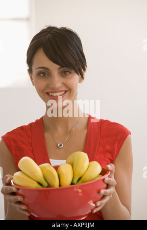 Young woman holding bowl of bananas Stock Photo