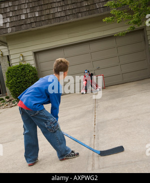 Boys playing hockey on driveway Stock Photo