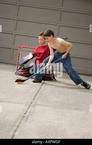 Boys playing hockey on driveway Stock Photo