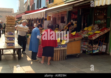 Locals buying from a Fresh Fruit and Vegetable shop on the main street of the island of Burano, Venice, Italy Stock Photo