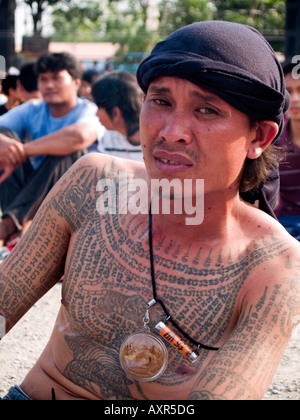 smoking tattooed man at the Wat Bang Phra Tattoo Festival in Thailand Stock Photo