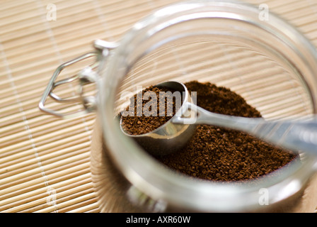 Coffee scoop filled with ground coffee (focus on it) in the glass jar. Shallow depth of field. Stock Photo