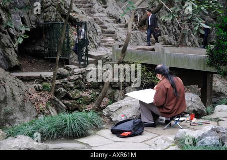 Artist painting stone carvings on the cliffs of the Peak Flying in from Afar at The Ling Yin Temple Hangzhou China Stock Photo