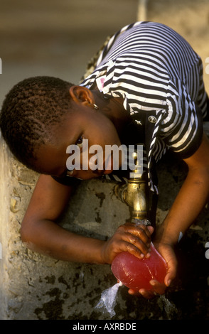 A pretty young girl filling a plastic bag with water at a standpipe in Maun Botswana southern Africa Stock Photo