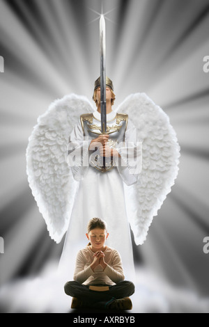 Girl praying with angel protecting her Stock Photo