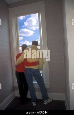Mature Couple Hug While Looking Out Window Stock Photo