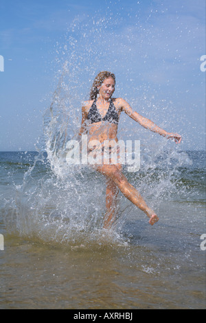 Young woman splashing in the shallow water of the sea, blurred motion Stock Photo