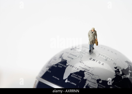 Businessman figurine with briefcase walking on globe Stock Photo