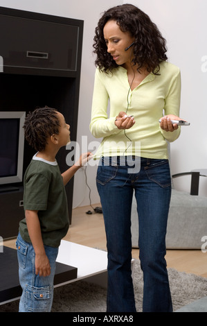 Portrait of a boy bothering his mom who is busy. Stock Photo