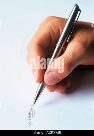 MAN'S HAND WRITING a SIGNATURE on a piece of paper with a silver ballpoint pen signing a document. England UK Britain Stock Photo