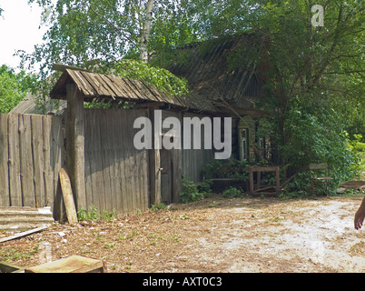 Occupied wooden house part log construction with corrugated roof faded wood fence adjacent, Chernobyl exclusion zone near Belarus Ukraine border Stock Photo