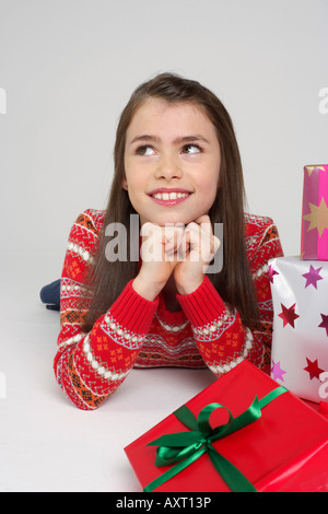 Smiling girl lying on front next to Christmas presents Stock Photo