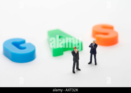 Two businessmen figurines standing next to the word Gas Stock Photo