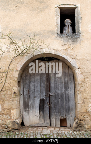 A wooden figure looks at the passers-by in one of the narrow streets of the french village of Flavigny-sur-Ozerain, Burgundy Stock Photo