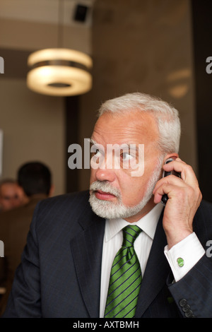 Mature businessman phoning with a mobile phone in a cafe Stock Photo