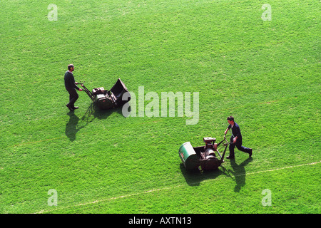 Groundsmen cutting grass on a sports pitch with mowers Stock Photo