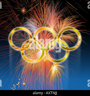 Golden olympic rings against fireworks over deep blue gradated background Stock Photo