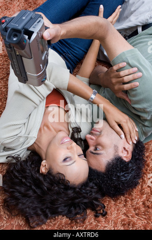 Portrait of a couple video recording while laying on the carpet. Stock Photo