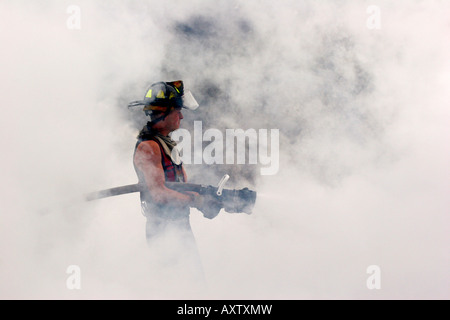 Firefighter holding a hoseline spraying the remaining fire Stock Photo