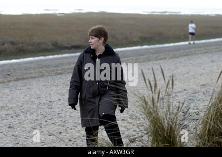 Woman out for a stroll along the Beach in Winter Stock Photo