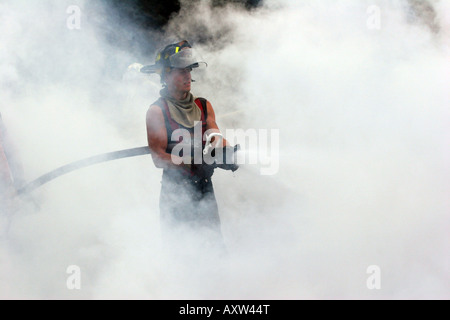 Firefighter holding a hoseline spraying the remaining fire Stock Photo