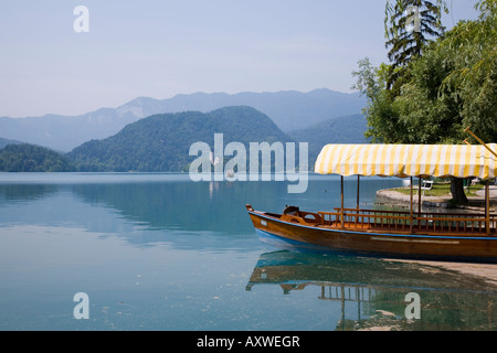 Traditional wooden pletnja to ferry tourists to St. Mary's Church of Assumption on the islet beyond, Lake Bled, Slovenia Stock Photo
