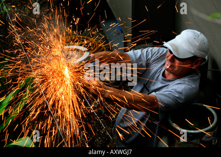 A worker uses a grinder with sparks flying off it Stock Photo