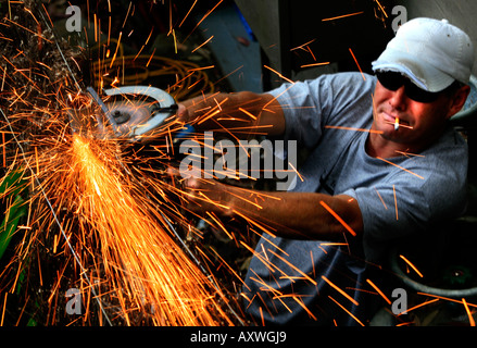 A worker uses a grinder with sparks flying off it Stock Photo