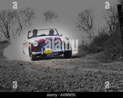 red rally Austin Healey 100/6 roadster at speed on gravel road at International horneland Rally Netherlands Stock Photo