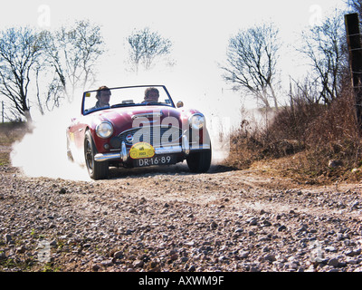 red rally Austin Healey 100/6 roadster at speed on gravel road at International horneland Rally Netherlands Stock Photo