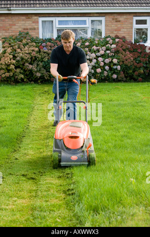 sunday afternoon waunfawr aberystwyth 1960 s suburban housing estate - a man mowing his lawn with an electric lawnmower Stock Photo