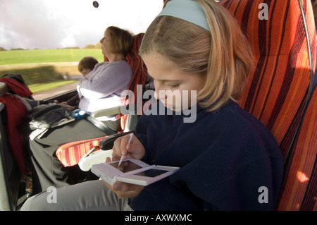 Twelve year old girl playing on her Nintendo DS computer game console while on a bus journey through south wales UK Stock Photo