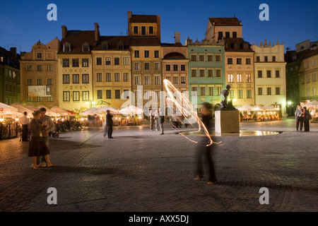 Street performers in front of houses, restaurants and cafes at dusk, Old Town Square (Rynek Stare Miasto), Warsaw, Poland Stock Photo