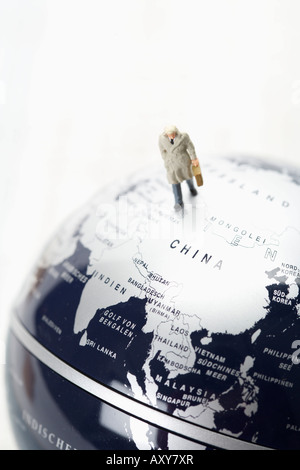 Businessman figurine with briefcase walking on globe Stock Photo