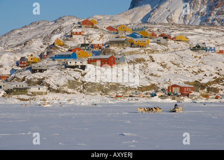 An inuit dog sled runs across the frozen harbour in Uummannaq, North West Greenland Stock Photo