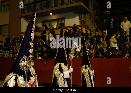 Three nazarenos wearing robes embroidered in gold and silk thread, Paso Blanco, Semana Santa, Lorca Stock Photo