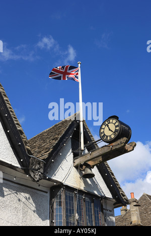 Flag clock over market house with its large clock, in the High Street of the small cotswold town of  Burford, West of Oxford Stock Photo