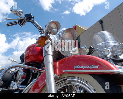 A bright metallic red Harley Davidson heritage softail in the sunlight with blue sky and clouds Stock Photo