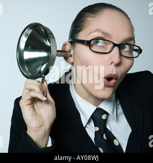 studio shot portrait of a beautiful curious business woman in a costume suit hearing aid funnel curious spying gossip Stock Photo