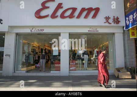 Monk walks past modern Etam clothes shop, Lhasa, Tibet Autonomous Region, China. Sept 06. Stock Photo
