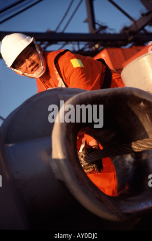 Hong Kong sailor at kwai chung container port on board tugboat feeding bow line through stanchion sar china fareast asia Stock Photo