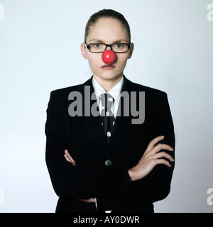 studio shot portrait of a beautiful one young business woman in a costume suit with a clown nose on isolated grey background Stock Photo