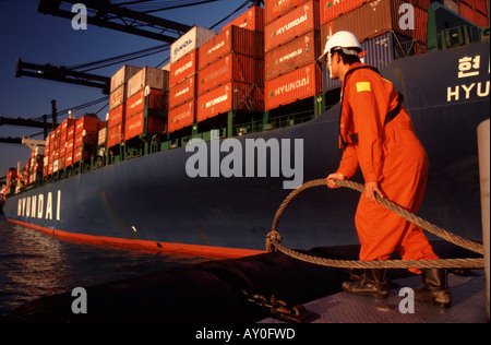 tugboat worker holding  mooring line ready to pass up to containership in kwai chung port hong kong fareast asia Stock Photo