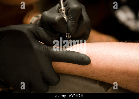 Tattoo artist on Easter Island working on a tribal tattoo for a tourist Stock Photo