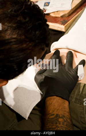 Tattoo artist on Easter Island working on a tribal tattoo for a tourist Stock Photo