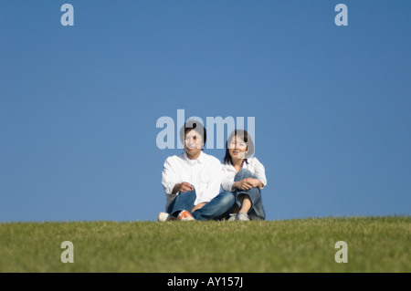 Mid adult couple sitting in field Stock Photo