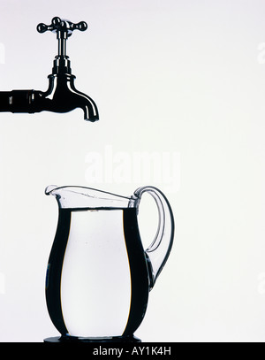 Tap with glass jug full of water Stock Photo