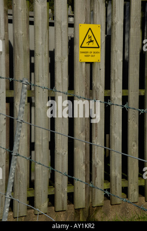 Sign saying 'Danger of Death: Keep Out' on picket fence behind barbed wire Stock Photo
