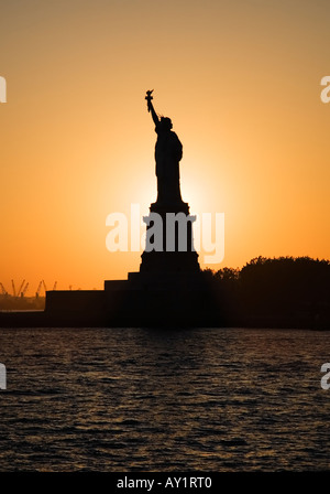 Statue of  Liberty in silhouette against the setting sun, Liberty Island, New York Stock Photo