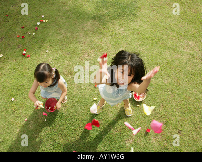 Portrait of two girls throwing rose petals in the air Stock Photo - Alamy